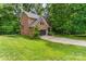 A charming two-story brick home sits on a lush green lot, surrounded by mature trees and features an attached two car garage at 530 Shady Oaks Dr, Stanley, NC 28164