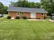 Exterior of a brick house featuring a well-manicured lawn and a concrete patio at 5734 Brookhaven Rd, Charlotte, NC 28210