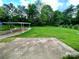 Expansive backyard with a concrete patio and a carport, surrounded by lush greenery and mature trees at 5734 Brookhaven Rd, Charlotte, NC 28210