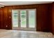 Inviting interior view with wood-paneled walls and tile flooring leading to a bright exterior through French doors at 5734 Brookhaven Rd, Charlotte, NC 28210