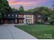 Striking modern home with a concrete driveway and well-manicured front lawn at sunset at 5925 Creola Rd, Charlotte, NC 28270
