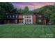 Striking modern home with unique architectural details, colorful sunset, and a well-manicured front lawn at 5925 Creola Rd, Charlotte, NC 28270