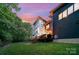 Contemporary home featuring a deck with string lights and a spacious lawn at twilight at 5925 Creola Rd, Charlotte, NC 28270