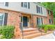 Inviting townhouse entrance with brick steps, black door with storm door, and well-maintained landscaping at 5927 Quail Hollow Rd # H, Charlotte, NC 28210