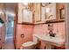 Vintage pink bathroom with pedestal sink, toilet, medicine cabinet and floral wallpaper at 611 E Marion St, Shelby, NC 28150