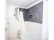 Bathroom featuring bathtub with shower, decorative tile surround, and window at 636 N Center St, Statesville, NC 28677