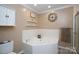A well-lit bathroom featuring a corner bathtub, decorative shelving, and a wall-mounted clock at 785 Sanside Dr, York, SC 29745