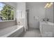 Bright bathroom featuring a bathtub under a window and a vanity with modern fixtures at 8441 Sandowne Ln, Huntersville, NC 28078