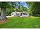 Charming single-story home featuring a well-manicured lawn, deck, and beautiful landscaping at 103 W Sunset Dr, Locust, NC 28097