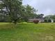 Expansive front yard features a classic home, mature trees, and a serene setting at 116 E Graves St, Candor, NC 27229