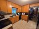 Functional kitchen with wooden cabinets, tile flooring, and a window over the sink at 116 E Graves St, Candor, NC 27229