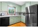 A full kitchen view showcasing green cabinets, stainless steel appliances, and a view from the kitchen window at 139 Pleasant Garden Dr, Taylorsville, NC 28681