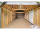 Spacious, unfinished shed interior with wooden beams, shelving, and a door at 139 Pleasant Garden Dr, Taylorsville, NC 28681