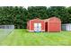 Backyard view of two red storage sheds with white trim, situated on a lush green lawn at 139 Pleasant Garden Dr, Taylorsville, NC 28681