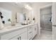Bright bathroom featuring double vanity with white cabinets, quartz countertops and tiled shower with glass door at 1431 Hubert Graham Way, Tega Cay, SC 29708