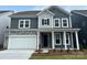Charming two-story home featuring stone accents, gray siding, a white garage door, and a welcoming front porch at 1431 Hubert Graham Way, Tega Cay, SC 29708