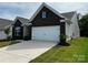 Brick home featuring a two-car garage, well maintained landscaping, and a manicured lawn at 147 Dubois Dr, Mooresville, NC 28115