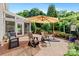 Cozy brick patio with seating and umbrella with view of the screened in sunroom at 16018 Hollingbourne Rd, Huntersville, NC 28078