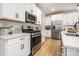 Bright kitchen features stainless steel appliances, white cabinets, quartz countertops and wood-look flooring at 16018 River Tree Ln, Charlotte, NC 28278