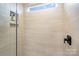 Walk-in shower featuring full tile surround with neutral colors, matte black fixtures, and recessed shelf at 16018 River Tree Ln, Charlotte, NC 28278