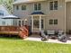 Large backyard with a wooden deck, brick patio area with seating, a lush lawn, and mature trees at 16028 Cranleigh Dr, Huntersville, NC 28078
