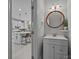 Stylish half bathroom with a round mirror and a view into the modern white kitchen at 16028 Cranleigh Dr, Huntersville, NC 28078