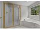 Bright bathroom featuring a glass-enclosed shower and a separate garden tub near a large window at 16028 Cranleigh Dr, Huntersville, NC 28078
