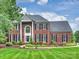 Stately brick home with lush landscaping, dark shutters, and manicured lawn at 16308 Woolwine Rd, Charlotte, NC 28278