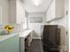 Well-organized laundry room with gray tile floors, white cabinets, washer, and dryer at 16308 Woolwine Rd, Charlotte, NC 28278
