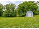 Expansive green backyard featuring a storage shed and mature trees, creating a serene and private outdoor oasis at 2024 Stonewyck Ave, Kannapolis, NC 28081