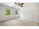 Bright bedroom with neutral carpet, ceiling fan, and large windows with views of the outdoors at 210 N Correll St, Landis, NC 28025