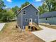 Rear exterior with dark siding, wooden stairs, and a newly poured concrete walkway at 210 N Correll St, Landis, NC 28025