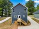 Exterior rear view of the house showcasing dark siding, wooden stairs, and concrete walkway at 210 N Correll St, Landis, NC 28025