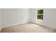 Bedroom with a neutral colored carpet, white walls, and a window overlooking the trees at 212 N Correll St, Landis, NC 28025