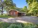 Charming brick home exterior featuring mature trees, covered parking area and access to a delightful sunroom at 2216 Griffith Rd, Monroe, NC 28112