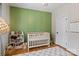 A charming Bedroom features a green accent wall, a white crib, and ample storage at 2217 Yadkin Ave, Charlotte, NC 28205