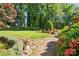 Serene backyard featuring a brick pathway, beautiful landscaping and a large shade tree at 308 Odell St, Kannapolis, NC 28083