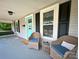 Inviting front porch featuring wicker chairs with blue cushions and a charming teal door with decorative accents at 329 Highland Dr, Lincolnton, NC 28092