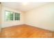 Bright bedroom featuring hardwood floors, light striped wallpaper, and a window overlooking greenery at 3526 Craig Ave, Charlotte, NC 28211