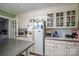 Cozy kitchen featuring white appliances, glass cabinets, tile countertops, and access to an adjacent room at 411 Hanna St, Gastonia, NC 28052