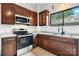 Kitchen featuring dark wood cabinetry, stainless steel appliances, tile flooring, and a stylish window at 425 1St Se Ave, Hickory, NC 28602