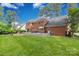 Expansive backyard featuring a brick home with a large deck, lush lawn, and mature trees at 5517 Alexa Rd, Charlotte, NC 28277