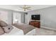 Cozy bedroom featuring a ceiling fan, carpeted floor, ensuite bathroom, and wooden dresser at 5517 Alexa Rd, Charlotte, NC 28277