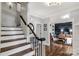 Bright foyer featuring hardwood floors, staircase with dark wood banister, and a glimpse into the adjacent living room at 5517 Alexa Rd, Charlotte, NC 28277