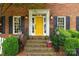 Inviting front porch with yellow door, brick steps, decorative lanterns, lush greenery, and a warm, welcoming ambiance at 5517 Alexa Rd, Charlotte, NC 28277