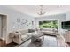 Bright living room featuring tufted sofas, hardwood floors, and a large window overlooking greenery at 5517 Alexa Rd, Charlotte, NC 28277