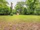 A large backyard with green grass, bordered by trees and a wooden fence, featuring a storage shed at 5629 Ruth Dr, Charlotte, NC 28215