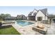Backyard with a luxurious pool, spa, stone patio and fire pit, next to a white brick house at 7215 Alexander Rd # 4, Charlotte, NC 28270
