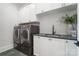 Laundry room with white cabinets, gray countertop, a stainless steel sink, and a washer/dryer at 7215 Alexander Rd # 4, Charlotte, NC 28270