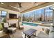Inviting covered patio with stone fireplace, tv, ceiling fan, and view of the pool and backyard at 7215 Alexander Rd # 4, Charlotte, NC 28270